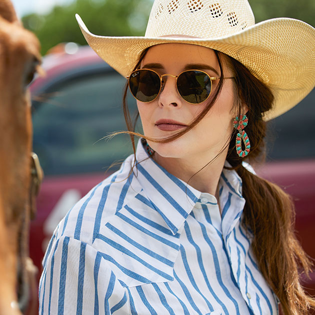 Cowgirl looks at her horse outside.